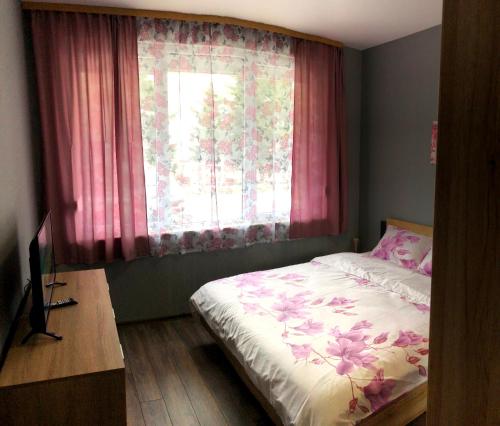 瓦尔纳Radost的一间卧室配有床和一个带粉红色窗帘的窗户。