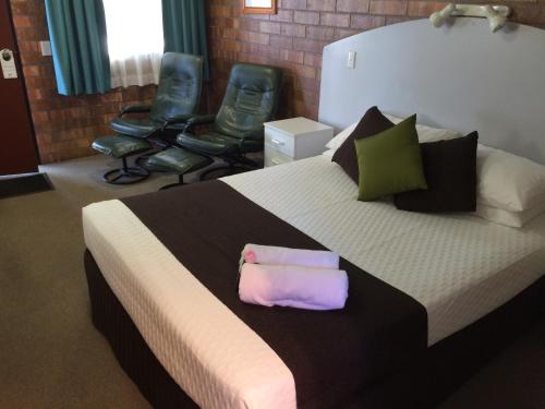 Miles迈尔斯奥拜汽车旅馆的一间卧室配有一张大床和两把椅子