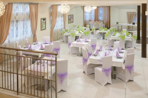 斯利亚奇那罗兹库膳食公寓酒店的用餐室配有白色的桌子和白色的椅子