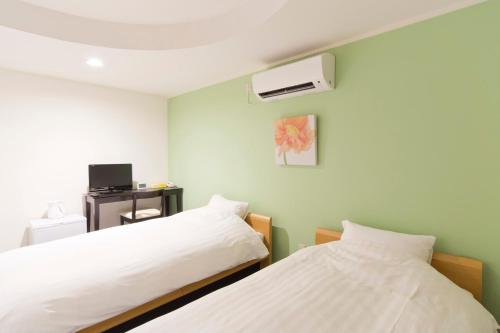 东京新大久保城市酒店的一间卧室配有两张床和空调。