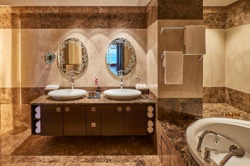 科威特科威特萨菲尔菲尼亚斯酒店的浴室配有2个盥洗盆、浴缸和镜子