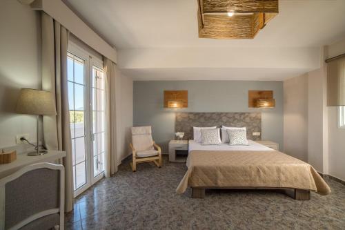 MouzákionBruma Luxury Residence的一间卧室配有一张床、一把椅子和窗户。