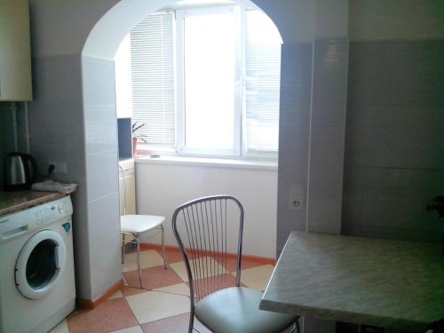 基辅Homelike flat near the IEC on Levoberezhnaya的厨房配有桌椅和洗衣机。