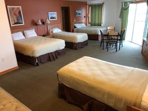 锡特卡Longliner Lodge and Suites的酒店客房,设有三张床和一张桌子及椅子