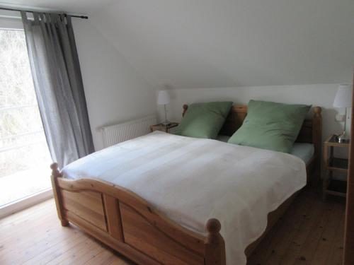布兰肯海姆EIFEL Gästewohnung的一间卧室配有一张带绿色枕头的大型木床。