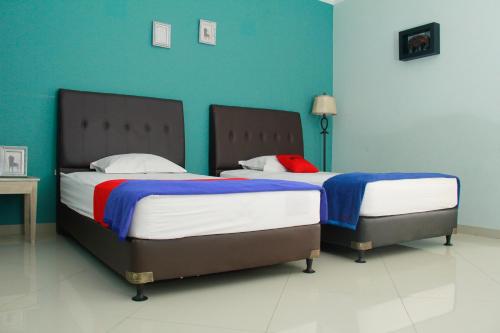 万隆赛尔森巴胡里红门旅馆的蓝色墙壁客房的两张床