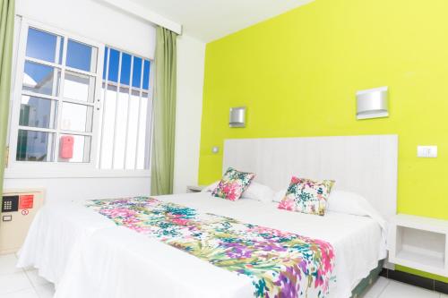 马斯帕洛马斯绿洲视野酒店的卧室配有白色的床和色彩缤纷的枕头