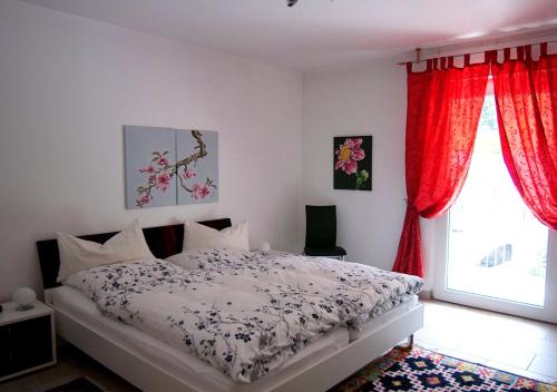 特拉本特拉巴赫Ferienwohnung-Mosel的一间卧室配有一张带红色窗帘的床和一扇窗户