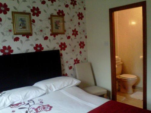 葛特纳格林查理王子小屋酒店的一间卧室配有一张床、一个卫生间和一面镜子