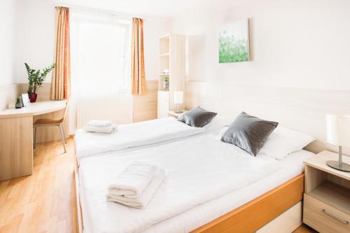维也纳myNext - Hotel Rudy的一间卧室配有两张带白色床单的床和一张书桌