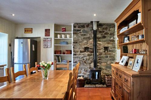 圣菲伦斯Glenalbyn Cottage的厨房配有木桌和石制壁炉。