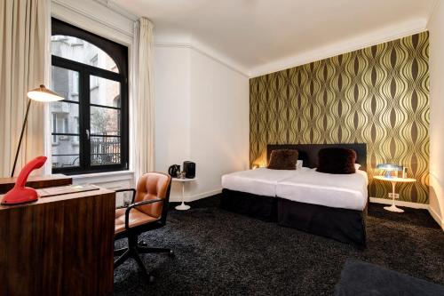 布鲁塞尔Vintage Hotel Brussels的酒店客房配有一张床、一张桌子和一把椅子。