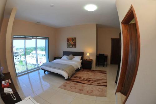 蒙罗维亚穆莱克斯广场酒店及套房的一间卧室设有一张大床和一个大窗户