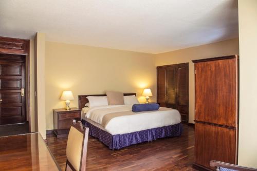 危地马拉征服者会议中心酒店 的一间卧室配有一张床、两张桌子和两盏灯。