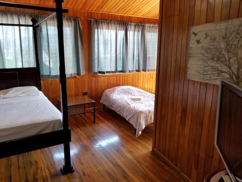 圣何塞Hotel Monte Campana Escazu的一间卧室配有一张床和一张床,面积有1平方米