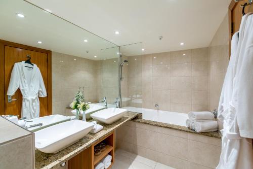 新普利茅斯Plymouth International的浴室设有2个水槽、浴缸和镜子