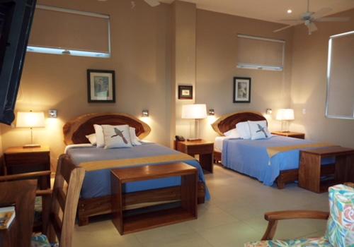 普拉亚埃尔莫萨Hotel La Gaviota Tropical的酒店客房,配有两张床和两把椅子