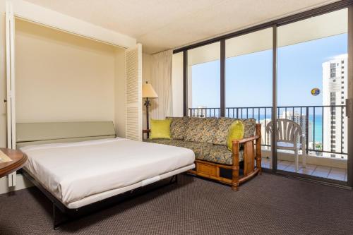 檀香山夏威夷阳光假日公寓的一间卧室配有一张床和一张沙发,并设有一个阳台