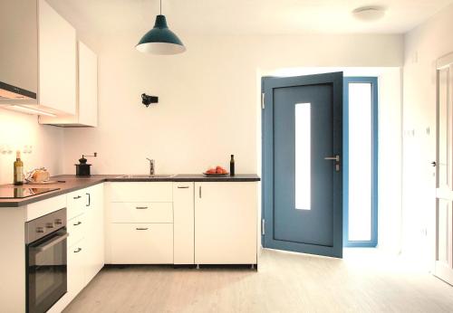 兹曼Apartmani Harmonija的厨房配有白色橱柜和蓝色门