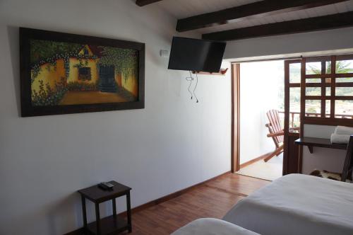 蒂瓦索萨San Benito Hotel的卧室配有一张床,墙上挂有绘画作品
