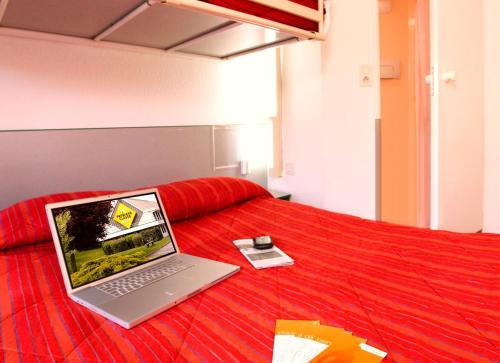 圣马丹-布洛涅Première Classe Boulogne sur Mer的一张位于红色床铺上方的笔记本电脑