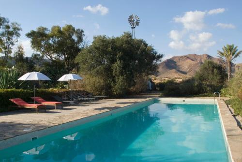 厄尔·坎皮洛·德·罗达尔伊尔加丁德罗斯罗苏诺思酒店的一个带椅子和遮阳伞的游泳池以及山地