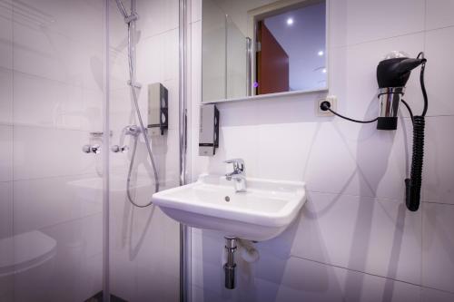 阿姆斯特丹阿姆斯特丹市中心酒店的带淋浴和盥洗盆的白色浴室