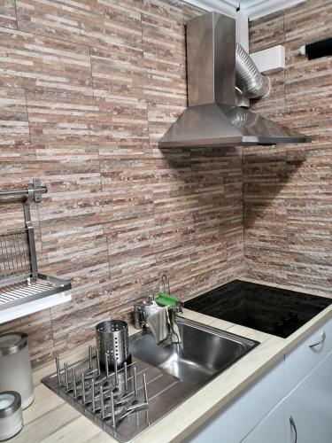 普拉亚达维多利亚Central Praia Beach House的厨房配有不锈钢水槽和砖墙