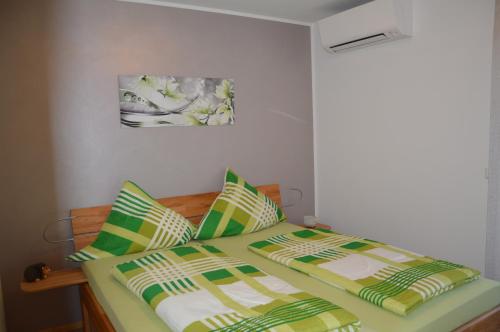 莱茵豪森Ferienwohnung Am Brunnen (Nähe Europapark)的一间卧室配有两张带绿色和黄色床单的床