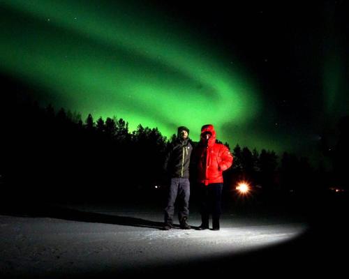 Sonka帕罗意罗马可山林小屋的两人站在绿色的北极光下