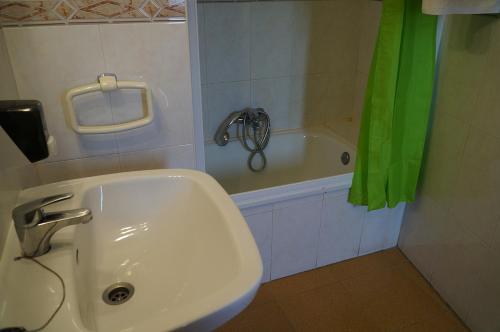 Calzadilla de la CuezaHostal Camino Real的浴室设有水槽和绿色的淋浴帘