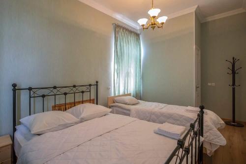 哥里Gogi Dvalishvili Wine Cellar的一间卧室设有两张床、一个窗户和一个吊灯。