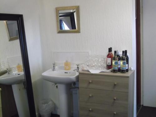 盖茨黑德Durham house hotel的浴室设有2个水槽和1个带瓶子及玻璃的梳妆台。