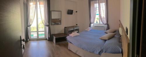 塞勒里古Hotel Marinella的一间卧室设有蓝色的床和2个窗户。