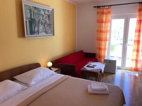 巴斯卡Summer rooms Baška的一间卧室配有一张床和一张红色的沙发