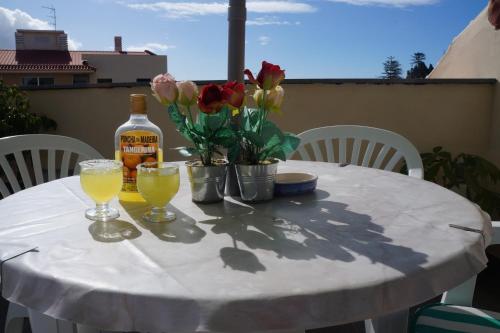 丰沙尔Casa Violeta的一张带一瓶葡萄酒和鲜花的白色桌子
