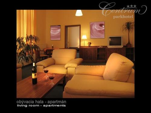 斯皮什新村中央公园酒店的客厅配有2张沙发和1瓶葡萄酒