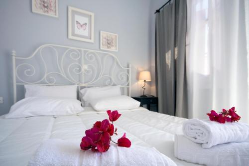 米克诺斯城阿罗度公寓的一张带毛巾的白色床和红色的鲜花
