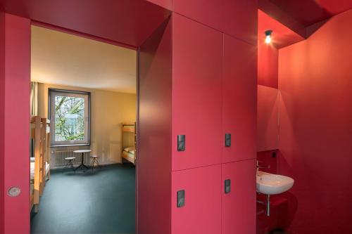 伯尔尼伯尔尼青年旅舍的一间带红色墙壁和水槽的浴室