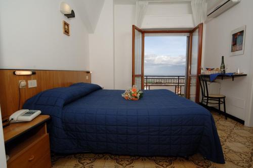 圣马力诺克罗赛斯酒店的一间卧室配有一张带蓝色毯子的床和窗户。