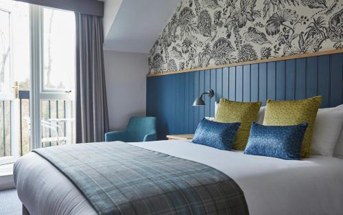 亨格福德The Bear Hotel by Greene King Inns的一间卧室配有一张带蓝色和黄色枕头的大床