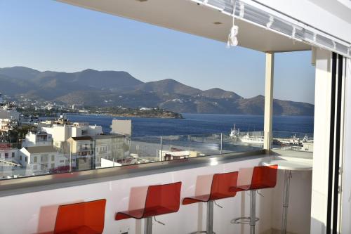 阿基欧斯尼古拉斯Ikaros Art Hotel的一间酒吧,配有红色的椅子,享有水景