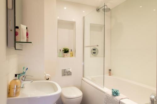 亨顿Finchley Central - Luxury 2 bed ground floor apartment的白色的浴室设有水槽、卫生间和淋浴。