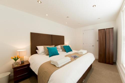 亨顿Finchley Central - Luxury 2 bed ground floor apartment的卧室配有带蓝色枕头的大型白色床