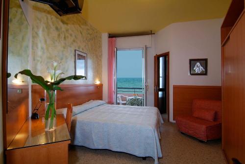 西尼加利亚Hotel Cristina的一间卧室,配有一张床,桌子上放着花瓶