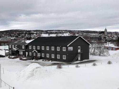 勒罗斯Rørosvidda Hotell的一座黑色的大建筑,地面上积雪