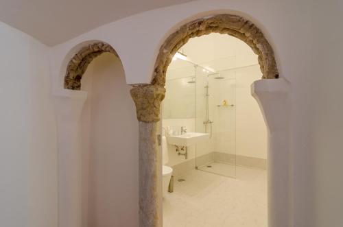 埃武拉Casa Morgado Esporao的带水槽和淋浴的浴室内的拱门
