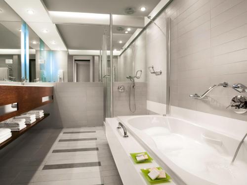 海法丹卡梅尔酒店的白色的浴室设有浴缸和淋浴。