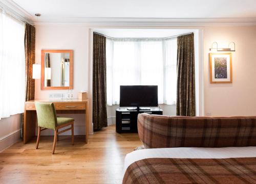 坎特伯雷坎特伯雷大住宿酒店的酒店客房配有一张床、一张书桌和一台电视。