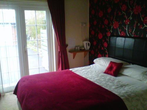葛特纳格林查理王子小屋酒店的一间卧室配有一张红色枕头的床
